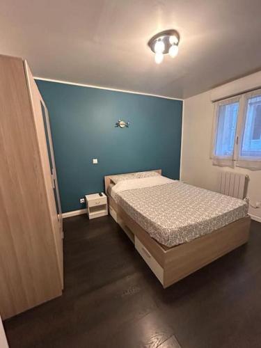 une chambre avec un lit et un mur bleu dans l'établissement Charmante dépendance Villejuif, à Villejuif