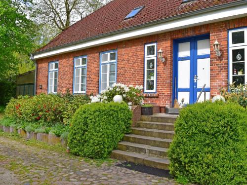 a red brick house with a blue door and stairs at Apartment in Schultenbrook with garden in Metelsdorf