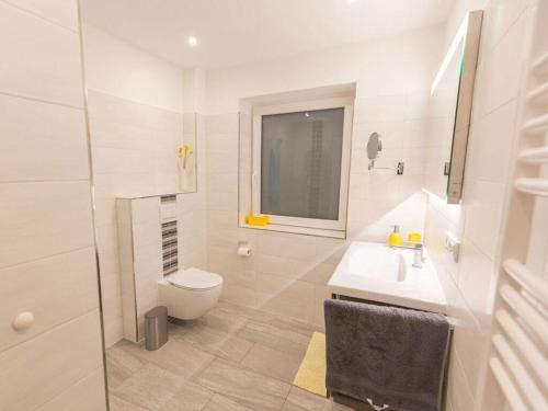 a white bathroom with a toilet and a sink at North Sea holiday home Zinnäcker in Almdorf