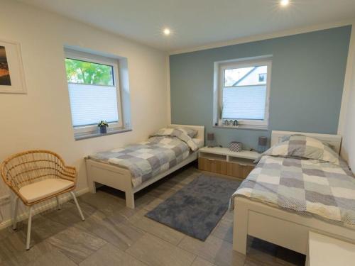 a bedroom with two beds and a chair and two windows at North Sea holiday home Zinnäcker in Almdorf