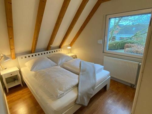a bedroom with a white bed with a window at Holiday home The Beach Hut in Schönhagen