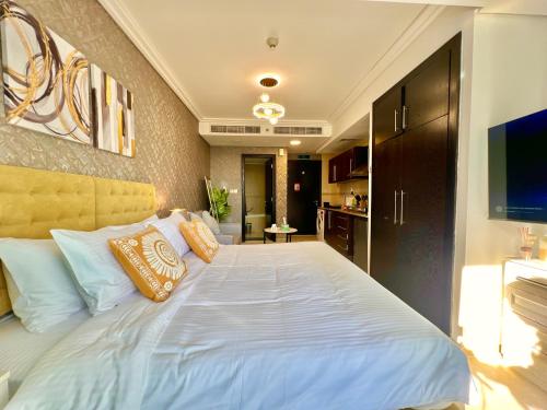 a bedroom with a large white bed with pillows at Cosmos Living Cozy Studio With Balcony in Dubai