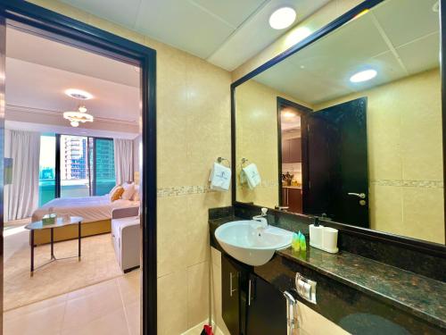 a bathroom with a sink and a mirror and a bedroom at Cosmos Living Cozy Studio With Balcony in Dubai