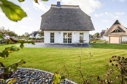 a house with a thatched roof on a lawn at Holiday house Fuhlendorf in Fuhlendorf