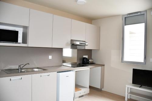 a white kitchen with a sink and a microwave at Domaine de l'Abbaye in Saint-Maur-des-Fossés
