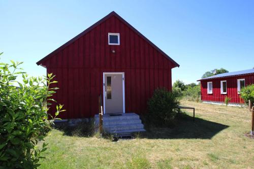 um celeiro vermelho com uma porta branca num campo em Holiday house at the Vilzsee Mirow em Diemitz