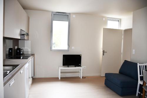 - un salon avec une télévision et un canapé bleu dans l'établissement Domaine de l'Abbaye, à Saint-Maur-des-Fossés