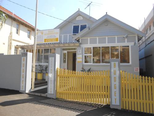 a house with a yellow fence in front of it at PodBed Coogee Beachside in Sydney