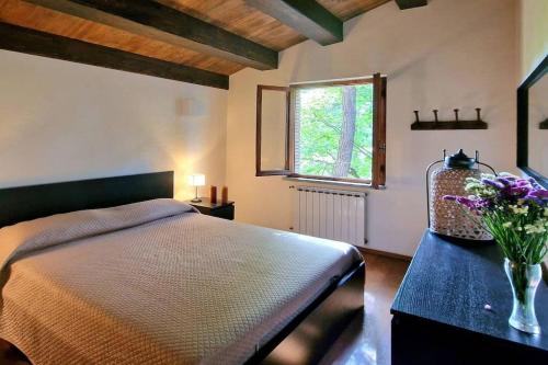 1 dormitorio con 1 cama y un jarrón de flores sobre una mesa en Villa Verde - Private Pool, en Pietralunga