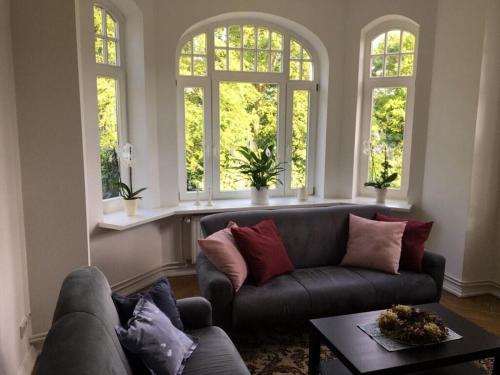 a living room with a couch and two windows at Art Nouveau villa am See in Ascheberg