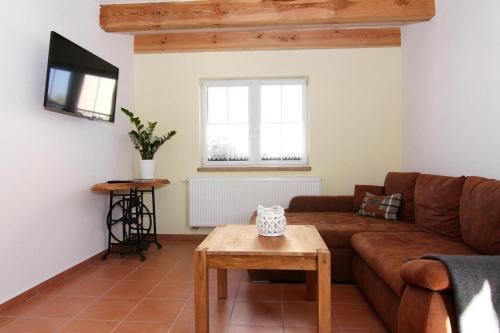 ein Wohnzimmer mit einem braunen Sofa und einem Tisch in der Unterkunft Farmstay Neuendorfkrug L tow in Lütow