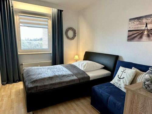 a bedroom with a bed and a couch and a window at Nice apartment near beach in Cuxhaven