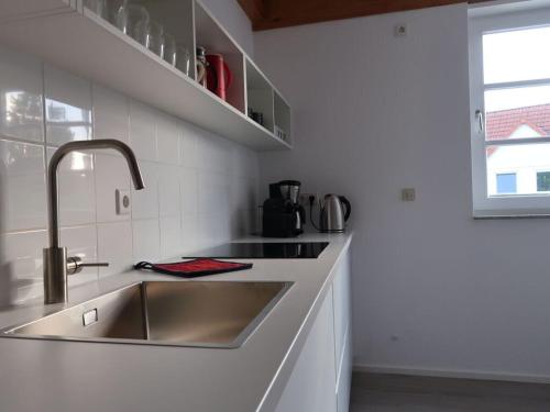 uma cozinha branca com um lavatório e um balcão em Modern apartment in the area of Hannov 
