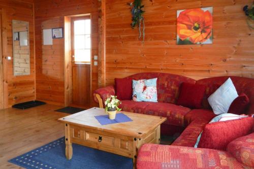 ein Wohnzimmer mit roten Sofas und einem Couchtisch in der Unterkunft Blockhouse in the Fuchsbau Bad Sachsa in Bad Sachsa