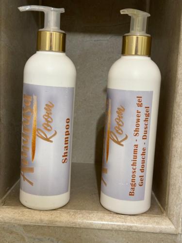 two white and gold bottles sitting on a shelf at Amurusa Room in Noto