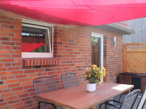 una mesa de madera con sillas bajo una sombrilla roja en Lovely Holiday Home in Zierow with Terrace en Zierow