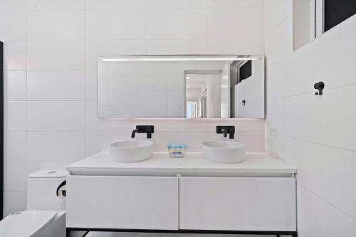 a white bathroom with two sinks and a mirror at Sabana Liber 12-R in Noord