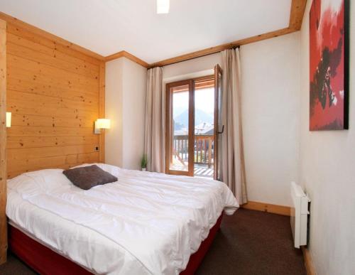 une chambre avec un lit et une grande fenêtre dans l'établissement Cortina 32 Appt terrasse somptueuse 4-6 pers, à Les Deux Alpes