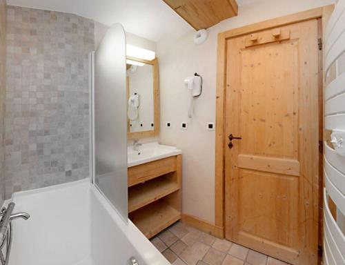 bagno con vasca, lavandino e specchio di Cortina 32 Appt terrasse somptueuse 4-6 pers a Les Deux Alpes