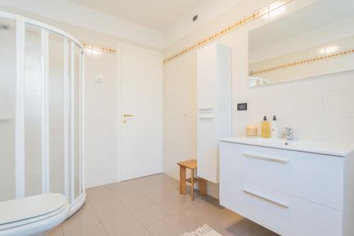 a white bathroom with a toilet and a sink at Ponente Balcony & Garden by Rent All Como in Gravedona