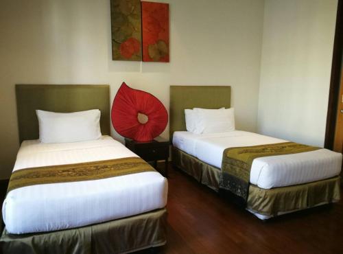 two beds in a hotel room with a red umbrella between them at Hua Hin Blue Lagoon in Cha Am