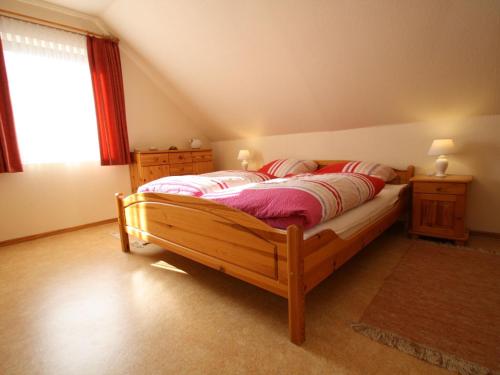 ein Schlafzimmer mit einem großen Holzbett mit roten Kissen in der Unterkunft Apartment house Schiefertal, Wieda in Wieda