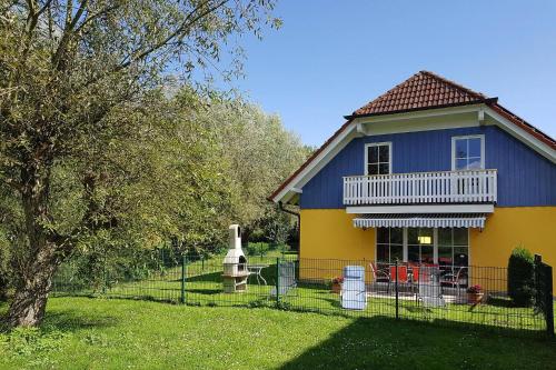 a yellow and blue house with a statue in the yard at Cottages at the Kummerower See Verchen in Verchen