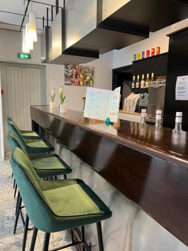 a row of green chairs at a bar at Adonis Arc Hotel Aix in Aix-en-Provence