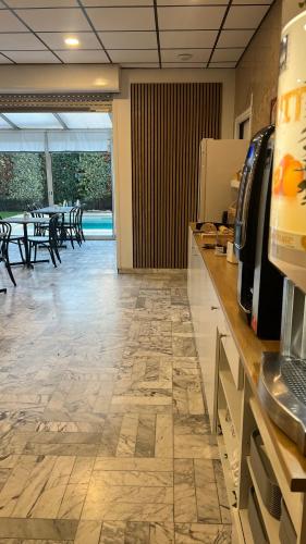 a kitchen with a counter and a dining room with tables at Adonis Arc Hotel Aix in Aix-en-Provence