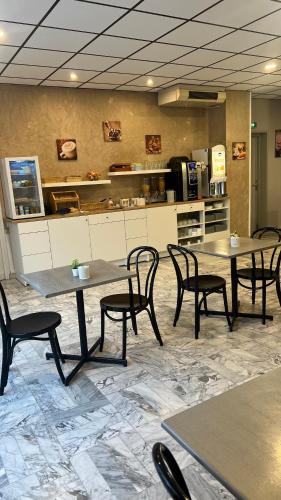 a restaurant with tables and chairs and a kitchen at Adonis Arc Hotel Aix in Aix-en-Provence