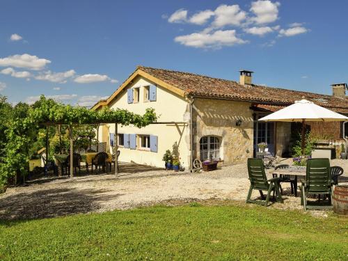 una casa con mesa, sillas y sombrilla en Snug cottage in Saint Eutrope De Born with pool, en Saint-Eutrope-de-Born