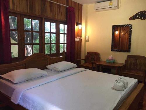 a bedroom with a large white bed with windows at บ้านสวนกุหลาบแก้วรีสอร์ท in Ban Mae Lai