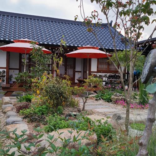 a garden with red umbrellas in front of a building at Hanok Raon in Gyeongju