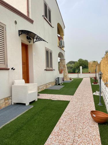 a garden with green grass and a white building at Janas B&B in Posada