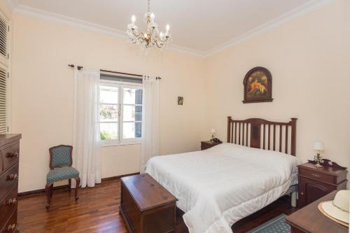ein Schlafzimmer mit einem Bett, einem Stuhl und einem Kronleuchter in der Unterkunft Bandama Country Home - 3BR with garden in Santa Brígida