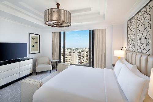 a bedroom with a white bed and a large window at The St. Regis Amman in Amman