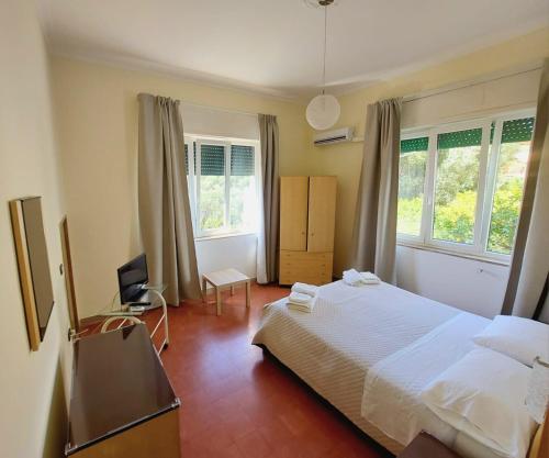 a bedroom with a white bed and two windows at Villa Silvia b&b in Marina di Camerota