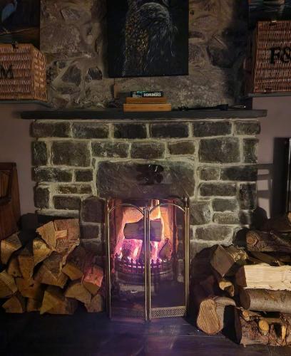 a brick fireplace with a fire in it at Harlech House in Harlech