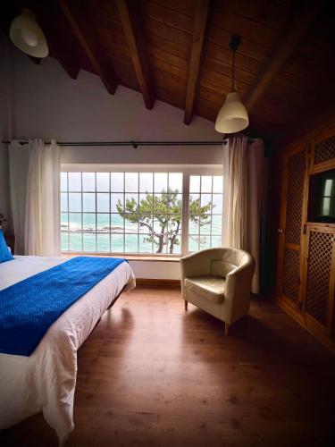 a bedroom with a bed and a chair and a window at Casas sobre el mar en Vigo in Vigo