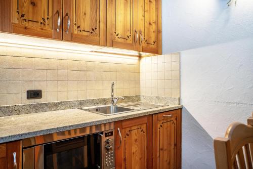 una cucina con armadi in legno e lavandino di Chalet Camping Faè 5 - Trilocale a Madonna di Campiglio