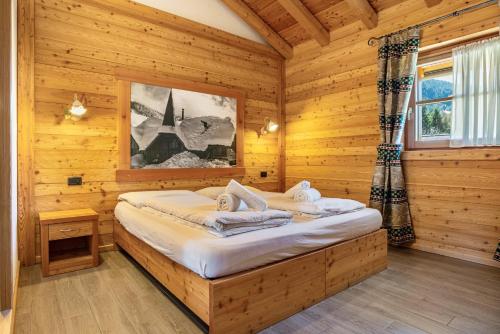 a bedroom with a bed in a wooden room at Chalet Camping Faè 5 - Trilocale in Madonna di Campiglio