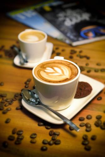 two cups of coffee on a table with coffee beans at Olive Tree Hotel Penang in Bayan Lepas