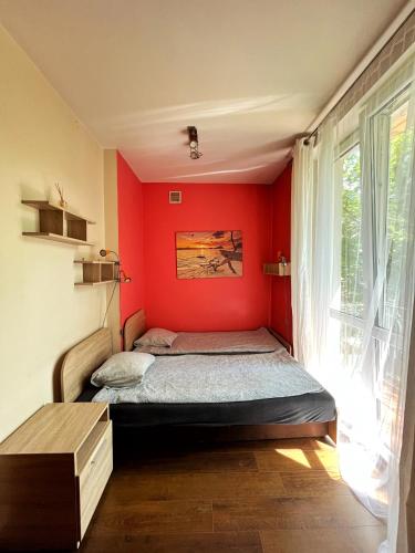 a bedroom with a bed with a red wall at Cosy room Aleja Kijowska in Krakow