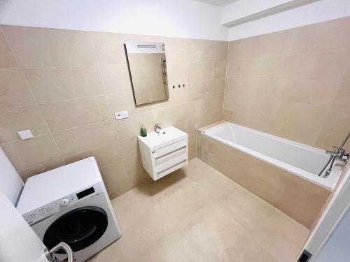 ein Badezimmer mit einer Badewanne, einem Waschbecken und einer Waschmaschine in der Unterkunft H5 apartman 2 bedrooms with balcony and free parking in Žilina