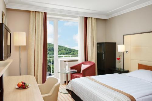 バート・ノイェンアール・アールヴァイラーにあるシュタインベルガー ホテル バード ノイエンナーのベッドと大きな窓が備わるホテルルームです。