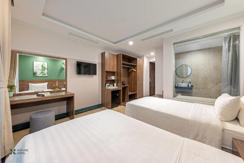 Habitación de hotel con 2 camas y escritorio en Nature Hanoi Hotel en Hanói