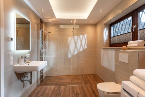 La salle de bains est pourvue d'un lavabo et de toilettes. dans l'établissement Ferienhaus Wildbarren - Alpenmagie Suites, à Oberaudorf