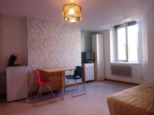 a bedroom with a bed and a desk with two chairs at Appartement Belley centre-ville in Belley