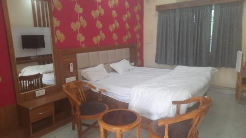 una piccola camera con un letto e due sedie di GANGA VATIKA a Varanasi