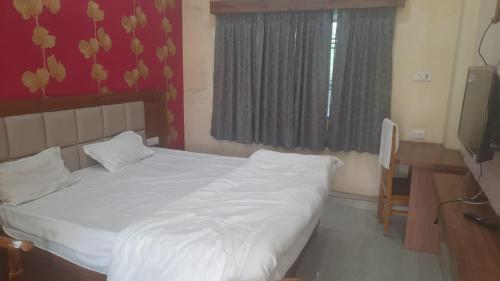 una camera con letto, scrivania e finestra di GANGA VATIKA a Varanasi